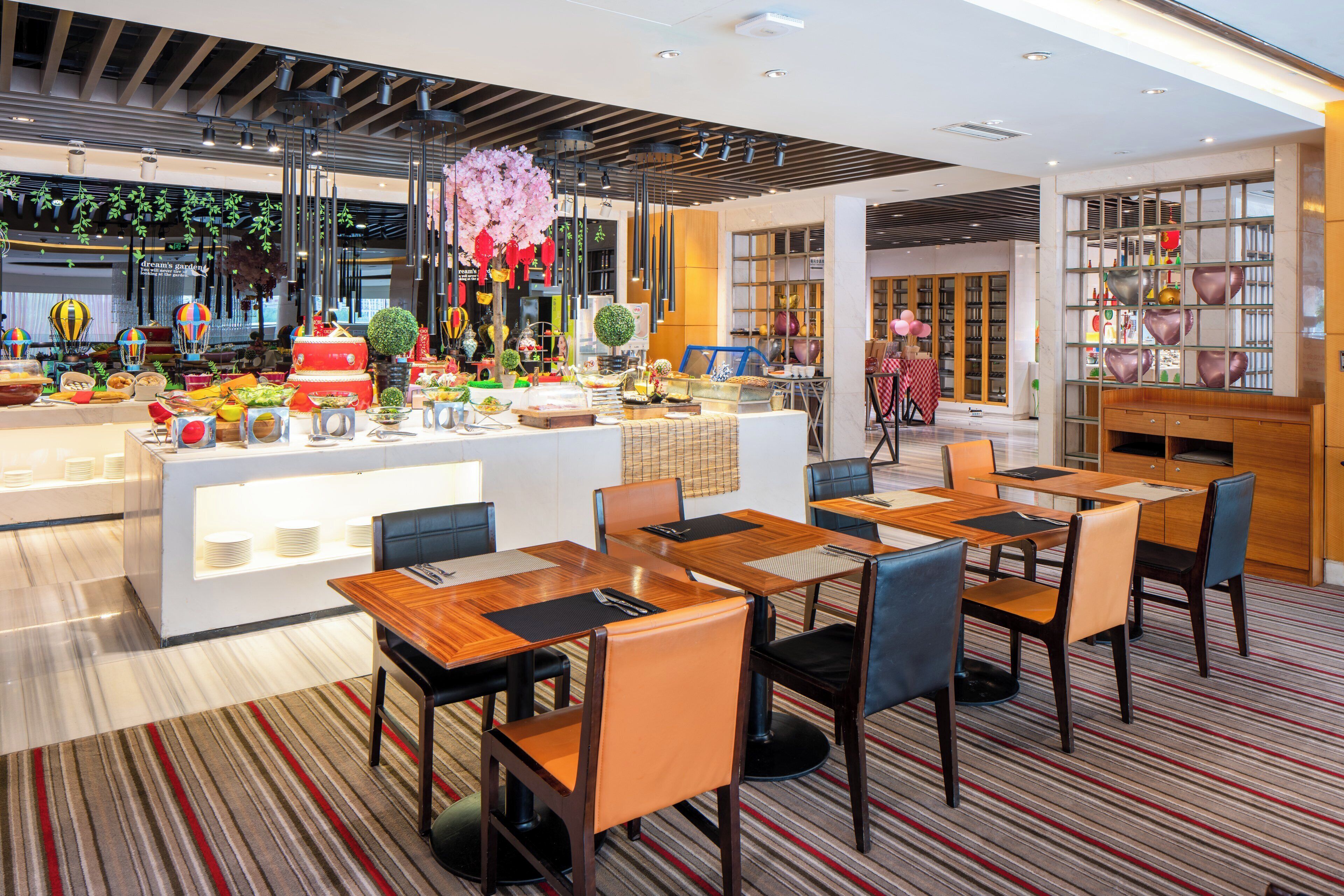 A modern dining area with a buffet setup, multiple tables, and chairs.