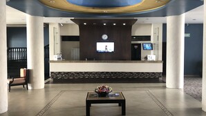 A lobby with a reception desk, a clock, and a floral arrangement on a table. - Hotel Playa Bonita (Mazatlán)