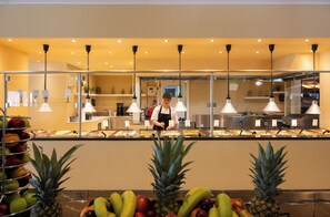 Un'area buffet con diversi tipi di frutta e una persona che serve.