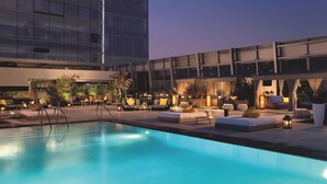 A rooftop pool area with lounge seating and a view of a modern building. - The Ritz-Carlton, Los Angeles (Los Angeles)