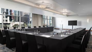Un salón de conferencias con una larga mesa, sillas y un amplio ventanal con vista a la ciudad.