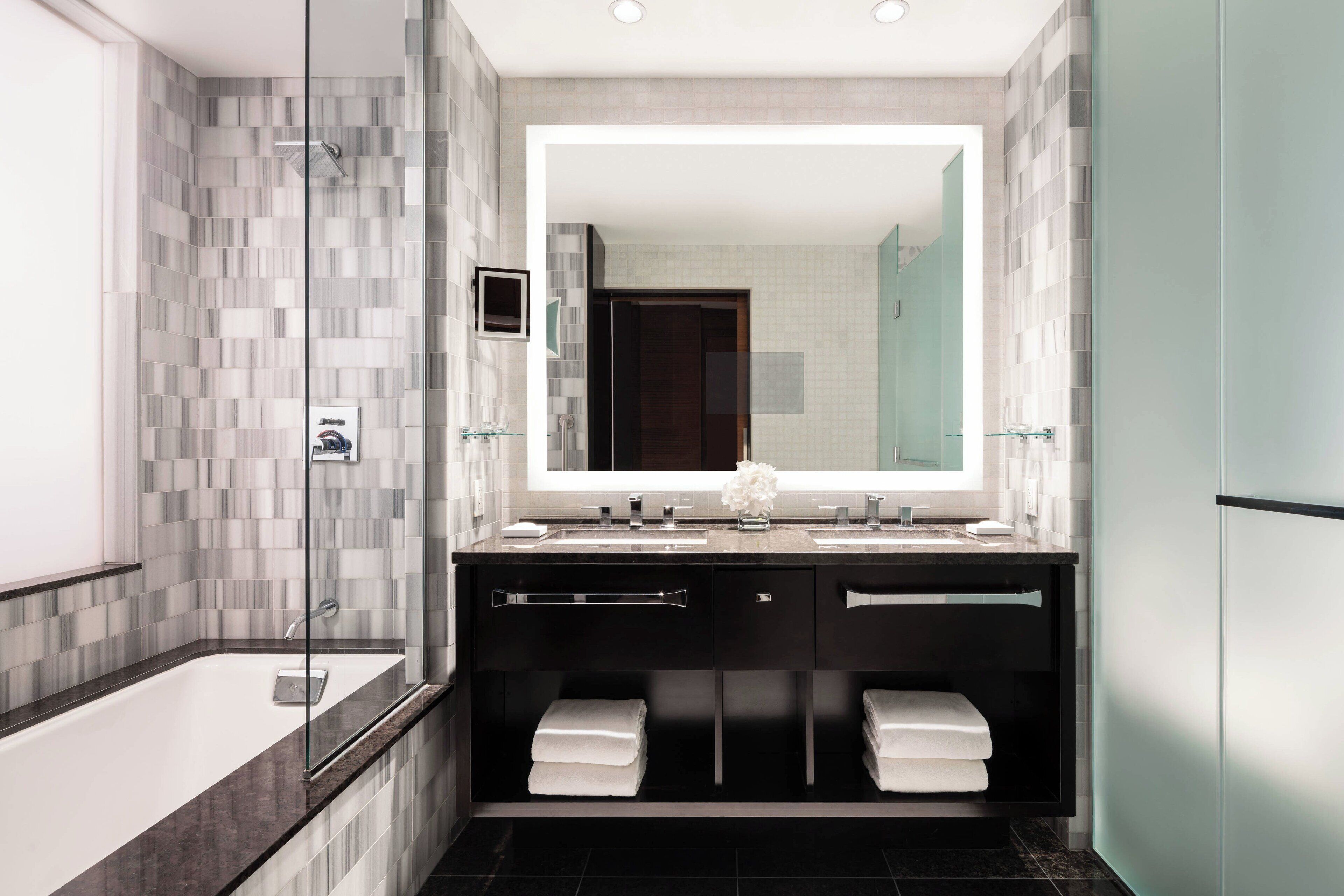 A modern bathroom with a glass-enclosed shower, a large mirror, and a dual sink vanity.