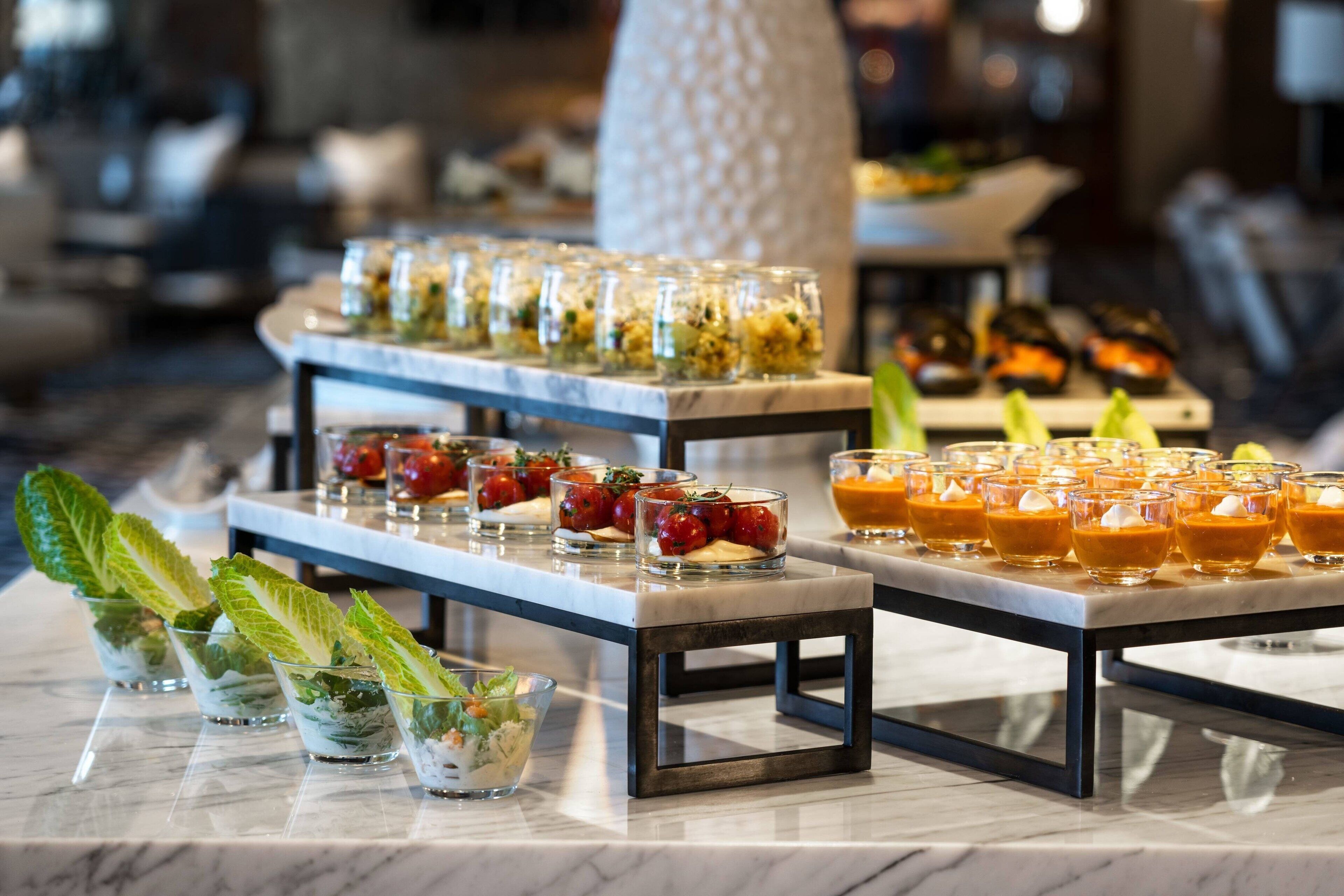 A buffet setup with various food items and drinks arranged on marble tables.