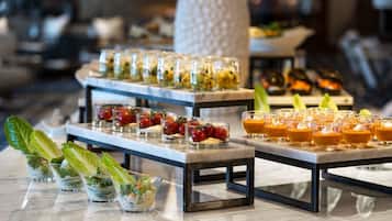 A buffet setup with various food items and drinks arranged on marble tables.