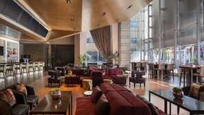 A spacious lobby with a bar area, seating arrangements, and large windows providing natural light. - The Ritz-Carlton, Los Angeles (Los Angeles)