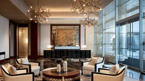 A modern lobby with a marble floor, two sofas, a coffee table, and a large mirror. - The Ritz-Carlton, Los Angeles (Los Angeles)