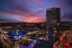 A cityscape at dusk with prominent buildings including The Ritz-Carlton and a large stadium.