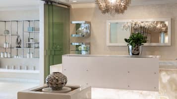 A modern reception area with a white reception desk, a decorative vase, and a mirror above it.