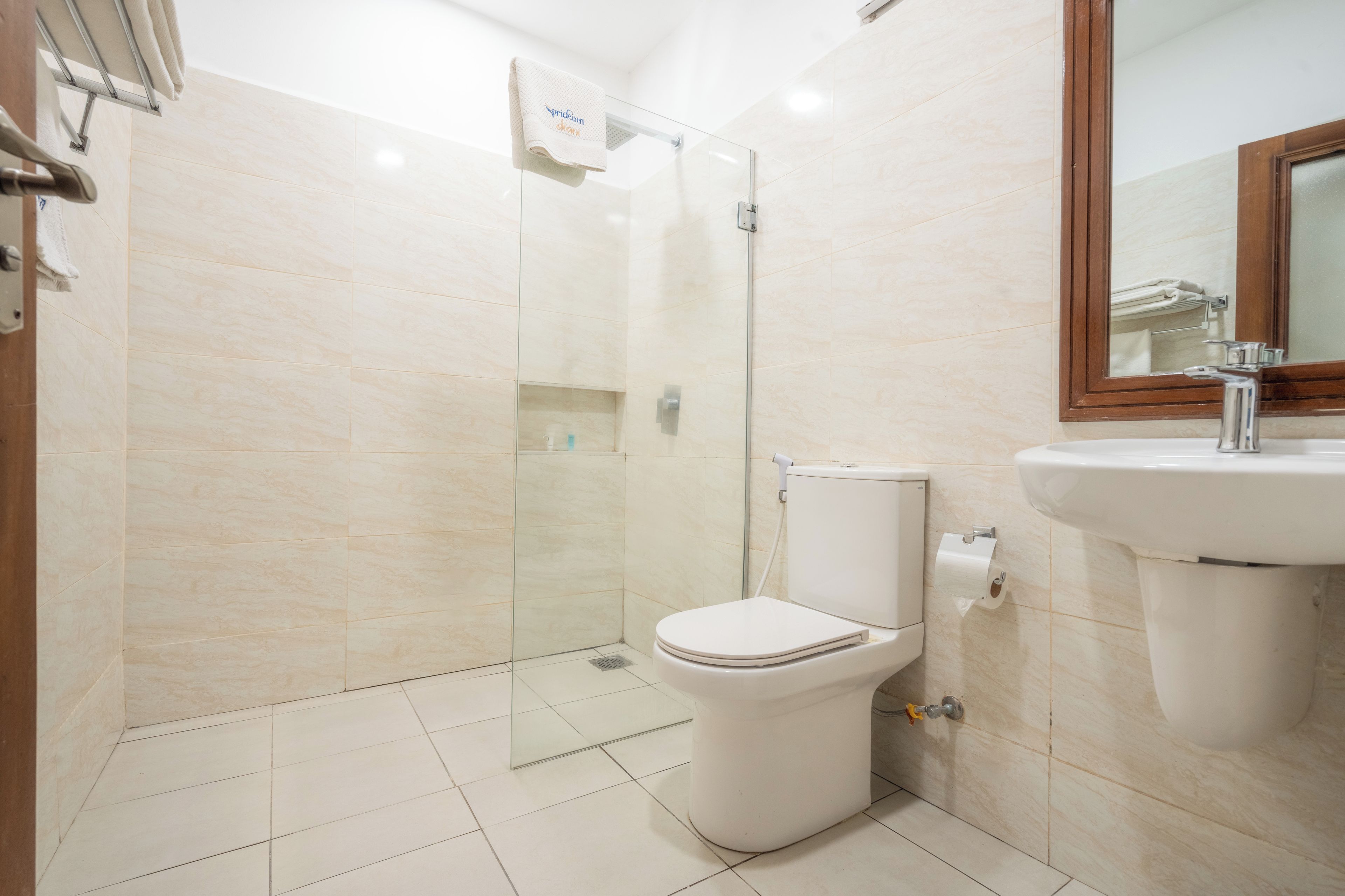 A bathroom with a glass-enclosed shower, a toilet, and a sink with a mirror above it.