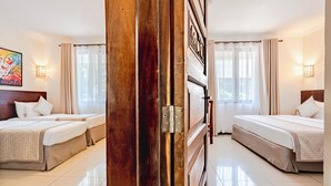 A hotel room with two beds, a wooden door, and a painting on the wall. - PrideInn Hotel Diani (Diani Beach)