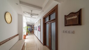 A hallway with a ceiling fan, a sign reading "KINANGO," and a potted plant. - PrideInn Hotel Diani (Diani Beach)