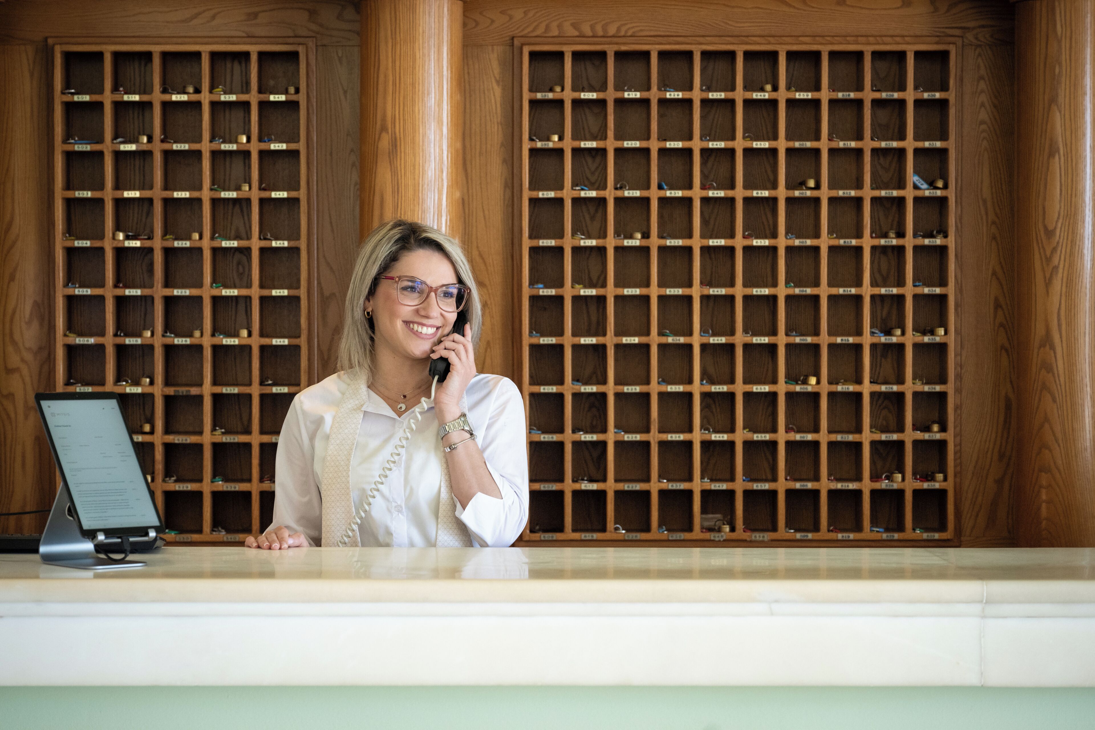 A reception desk with a wooden panel wall behind it, a computer monitor, and a telephone.