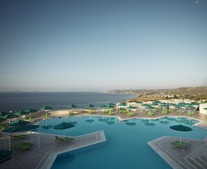 A pool area with multiple sections, each with green umbrellas and lounge chairs, overlooking a coastal landscape. - Canvas by Mitsis Family Village (Kos)
