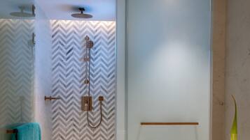 Un baño moderno con cabina de ducha de vidrio, suelo de mármol y diseño minimalista.