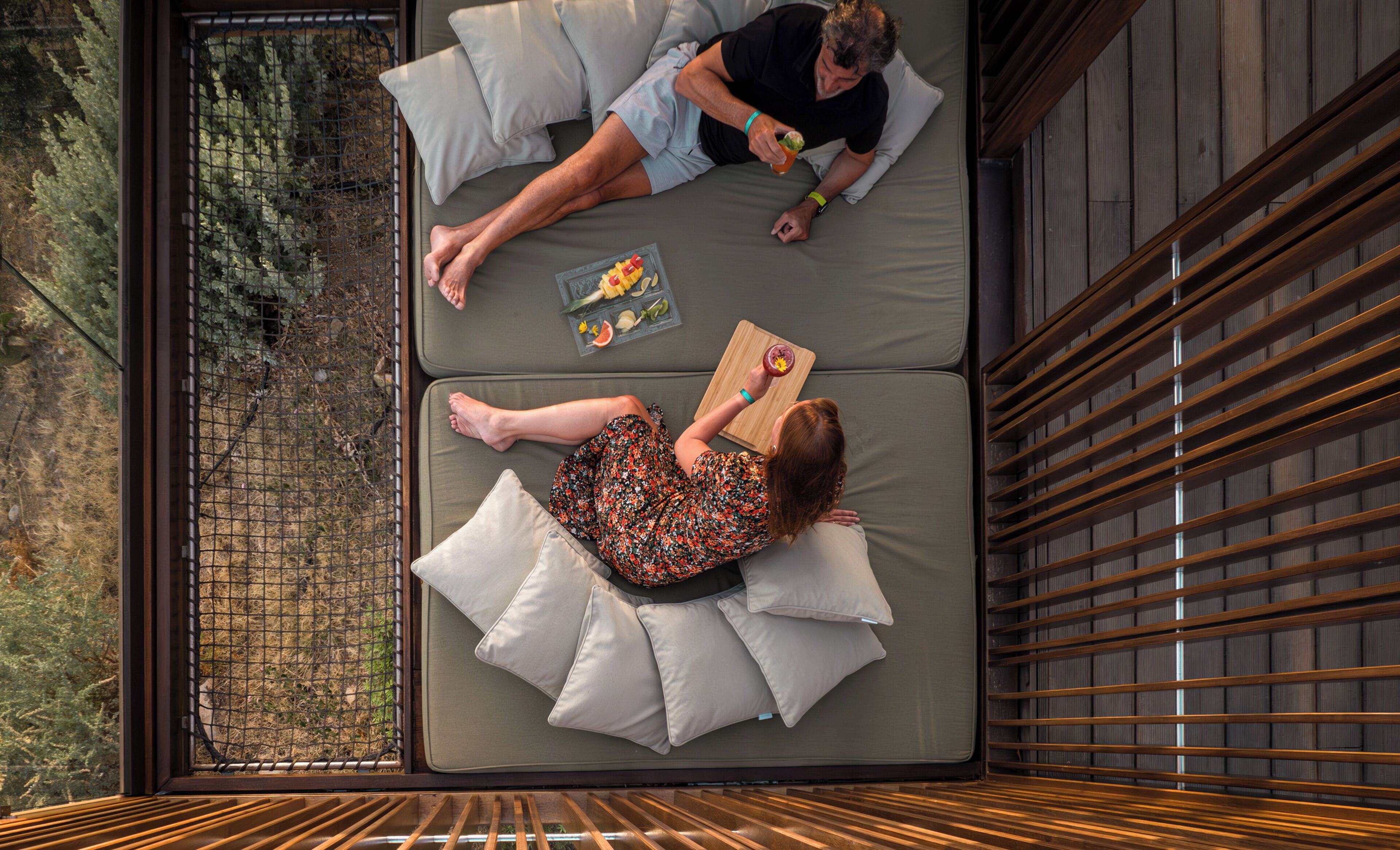 Ein Zimmer mit einem Bett, einem kleinen Tisch mit Obstschale und einem Fenster mit Blick auf Grünflächen.