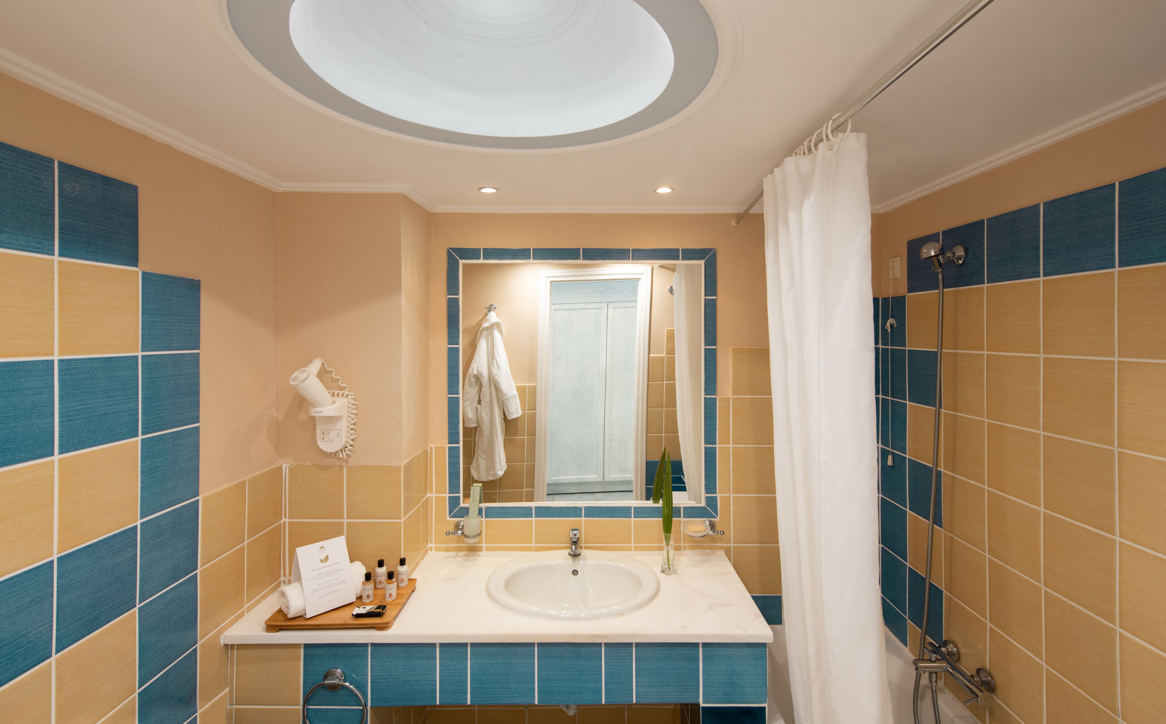Un baño con lavamanos, espejo, toallero y cortina de ducha.