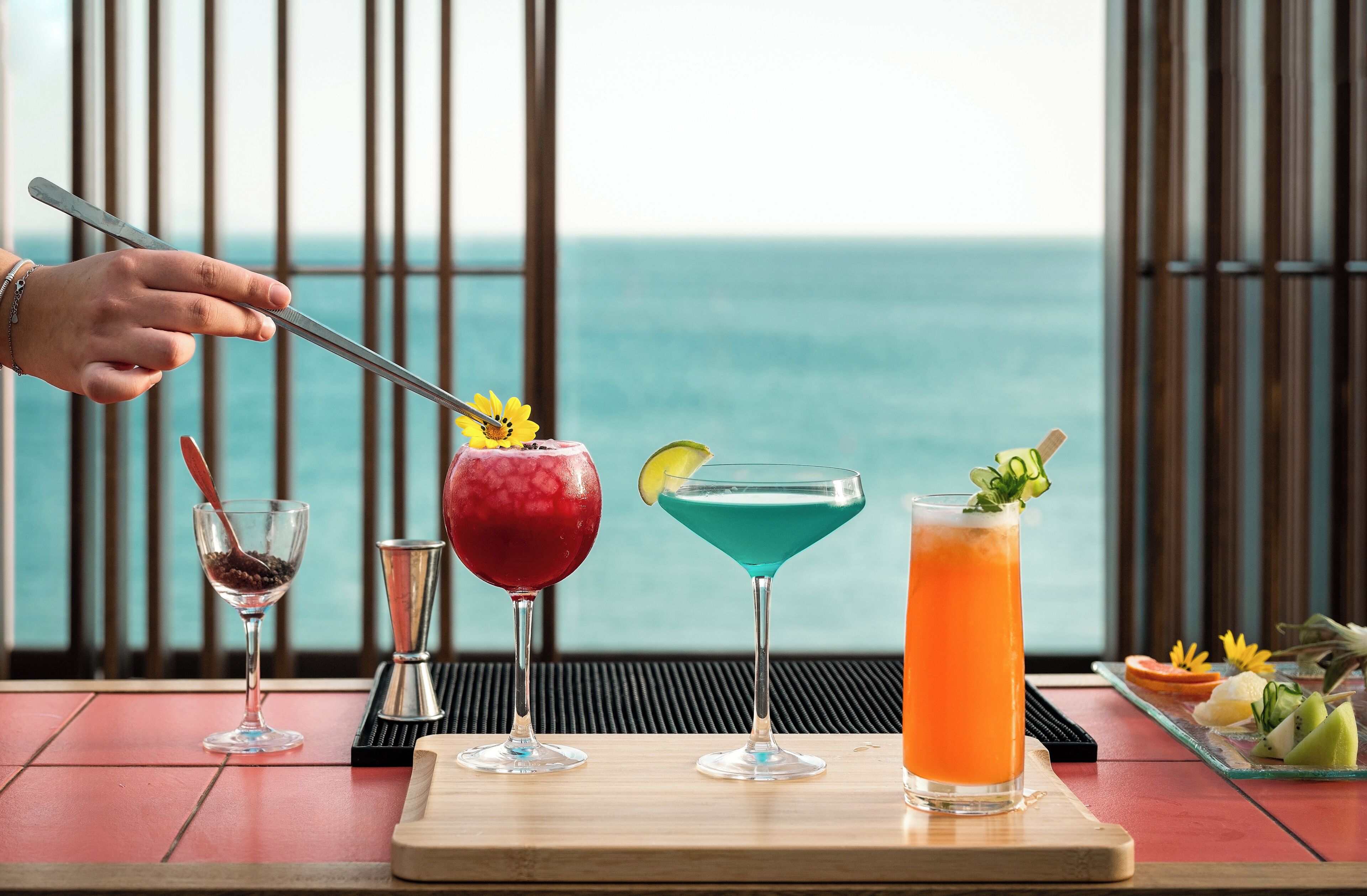 Une table avec quatre boissons, un couteau et un plateau de fruits.