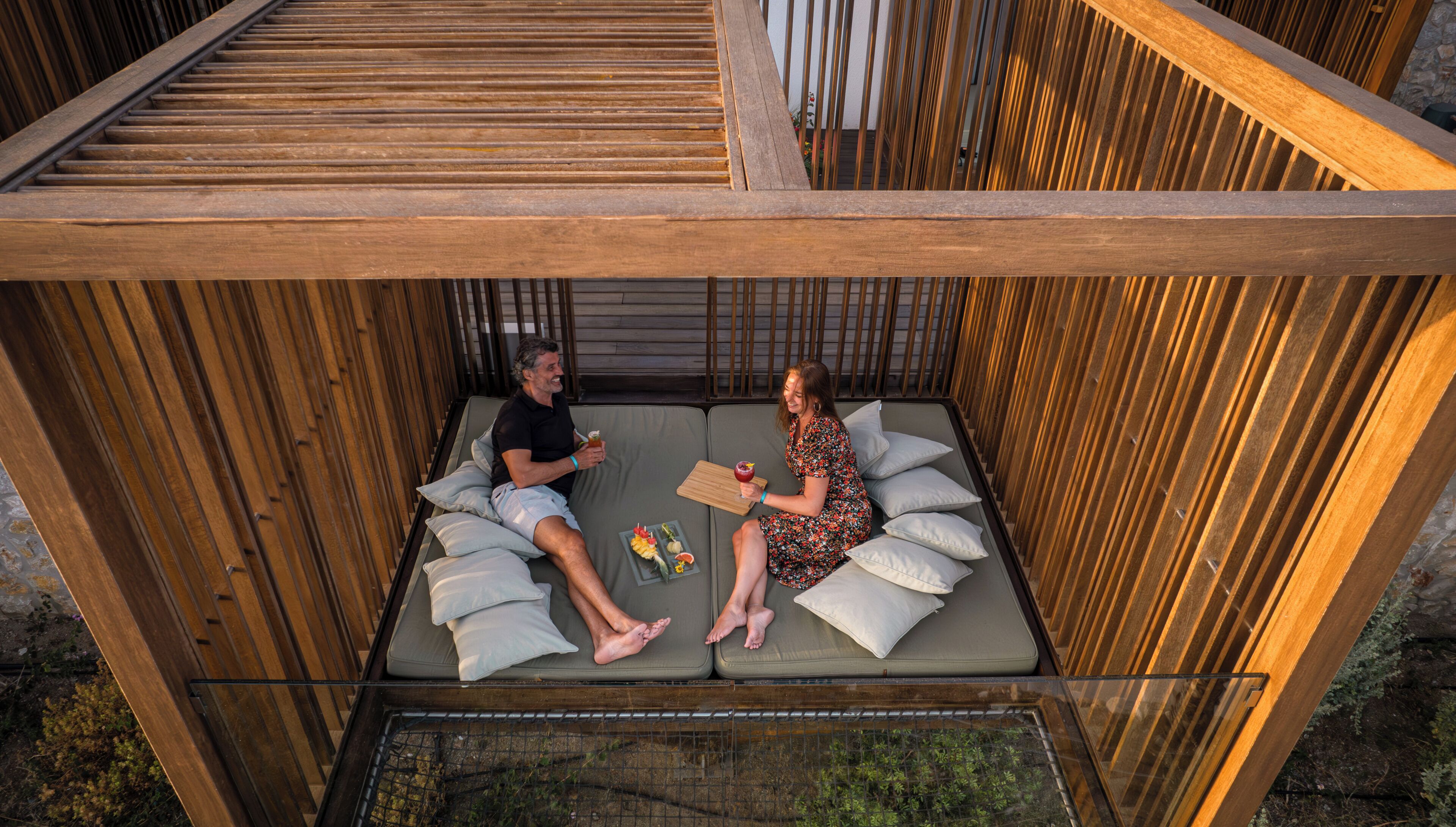 A wooden deck with two reclining chairs, a small table, and a glass barrier.