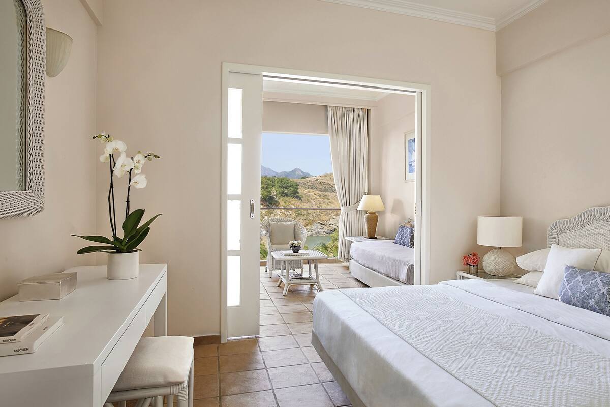 A hotel room with a bed, a desk, a chair, and a view of the outdoors.