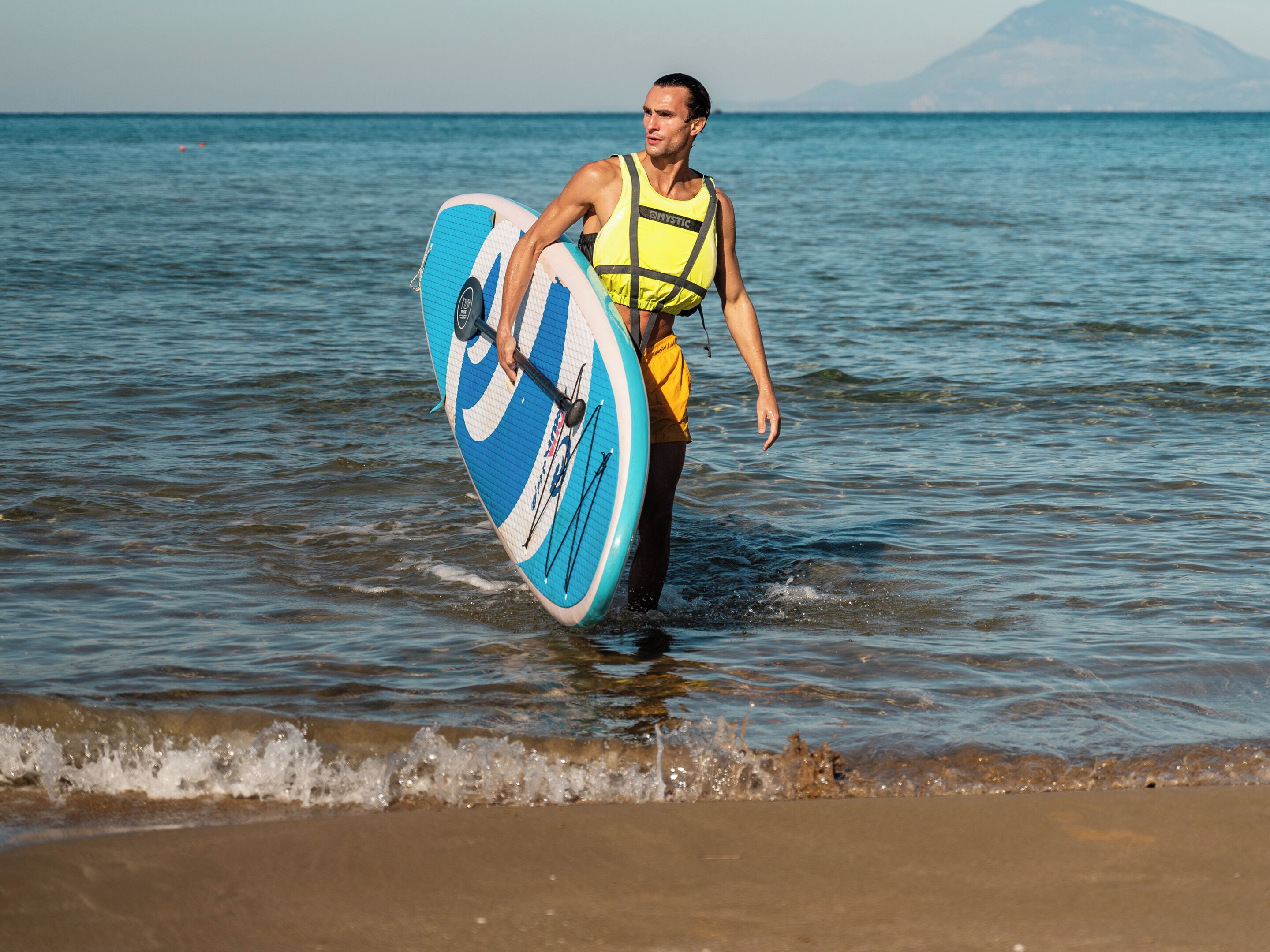 A person walking with a surfboard in a coastal area.