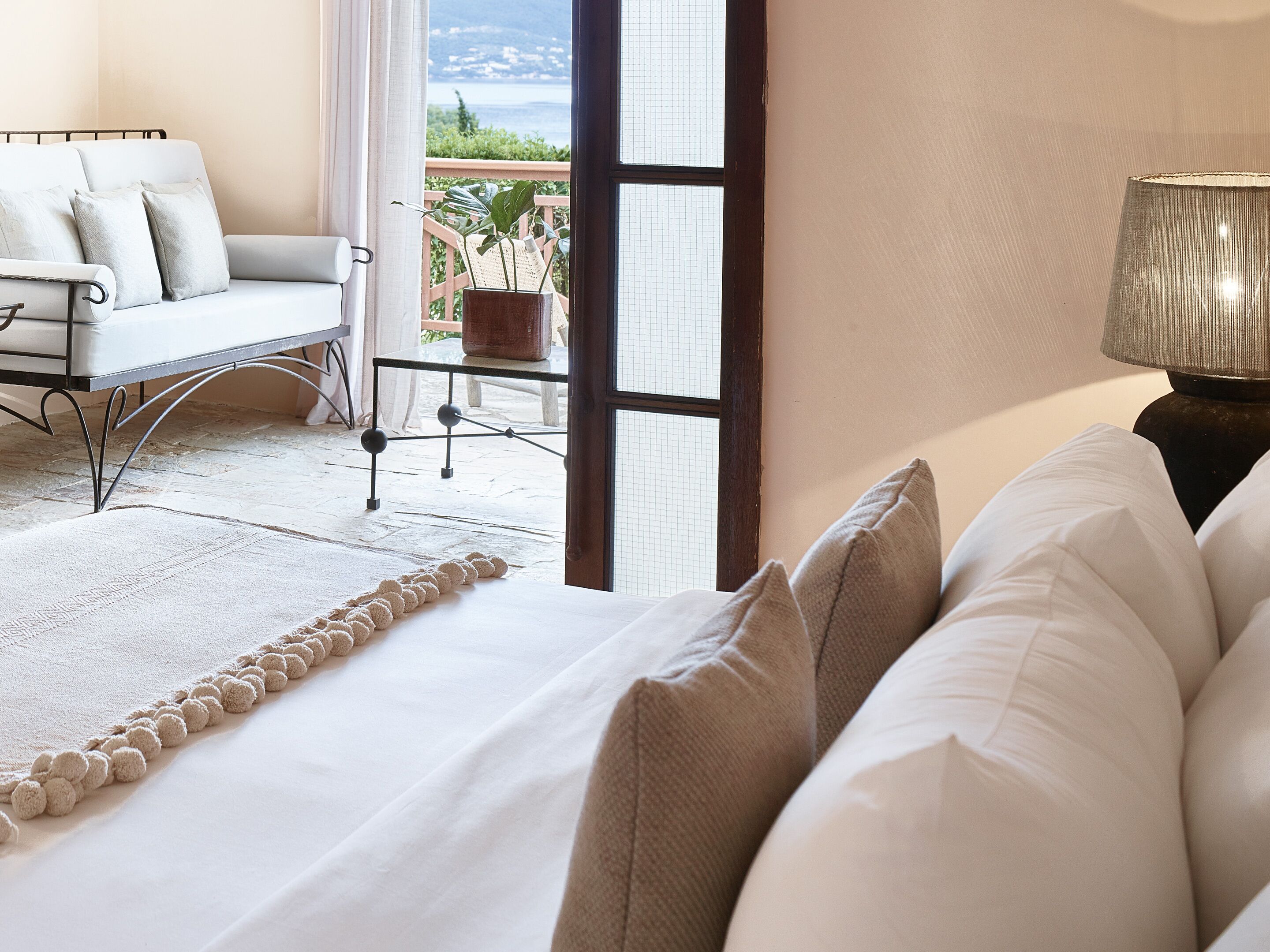 A bedroom with a bed, a view of the outdoors, a chair, and a table.