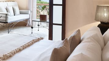 A bedroom with a bed, a view of the outdoors, a chair, and a table.