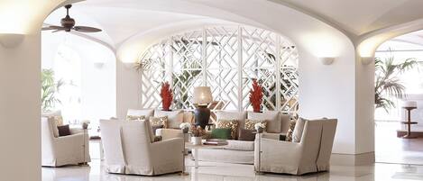 A spacious lobby with a high ceiling, a ceiling fan, and a seating area with sofas and a coffee table.