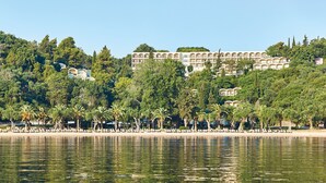 Un hotel sul lungomare con area piscina, palme e sullo sfondo edifici a più piani.