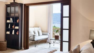 Un dormitorio con una cama grande, una estantería, un balcón con vistas y una silla.