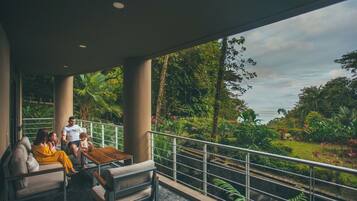 A balcony with a view of lush greenery and a body of water.