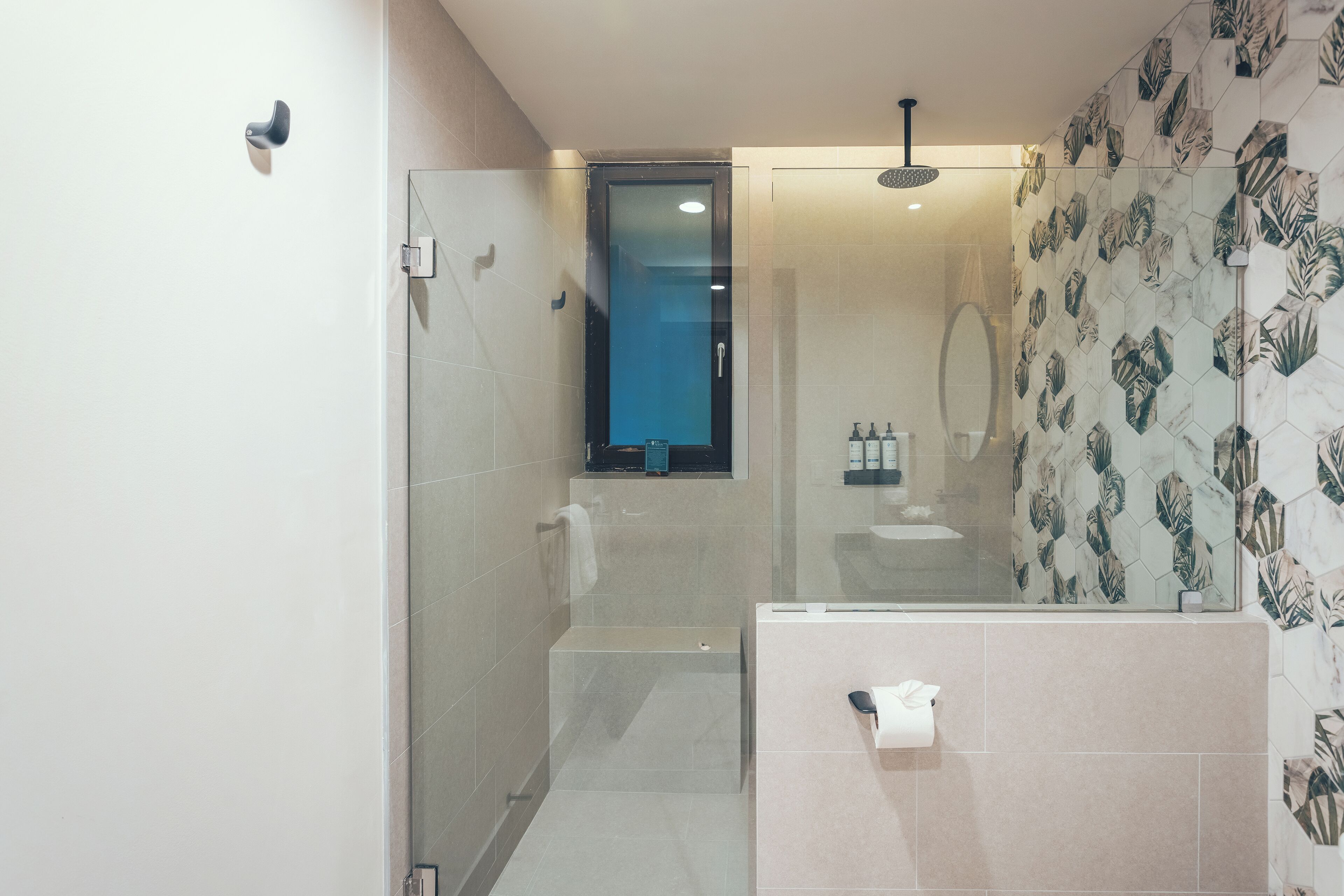 Ein modernes Badezimmer mit einer Duschkabine aus Glas, einem sichtbaren Toilettenpapierhalter und einer Duschbrause.