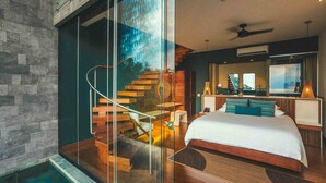 Un dormitorio moderno con una cama grande, una pared de cristal, una escalera de madera y vistas al exterior.