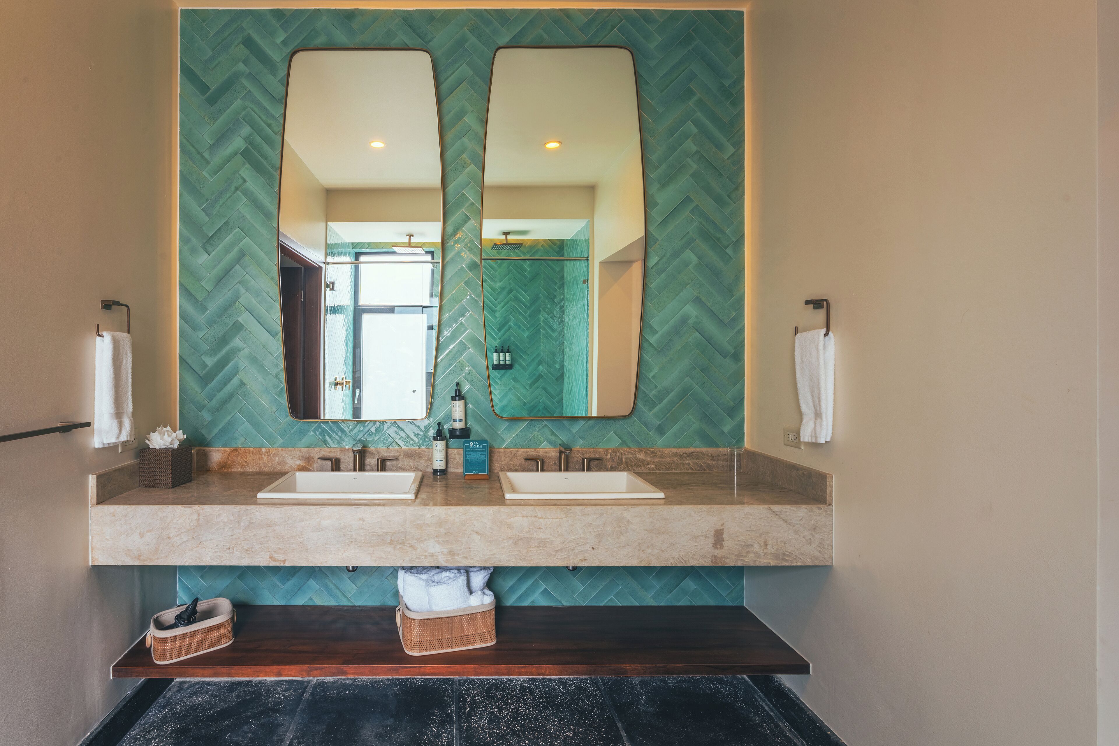 Un baño con dos lavamanos, un espejo grande y una pared con patrón de espiga.