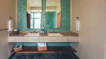 Un baño con dos lavamanos, un espejo grande y una pared con patrón de espiga.