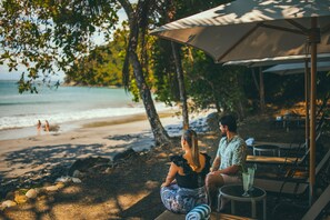 Rannalla, mustaa hiekkaa, ilmaiset rantakuljetukset, aurinkotuoleja