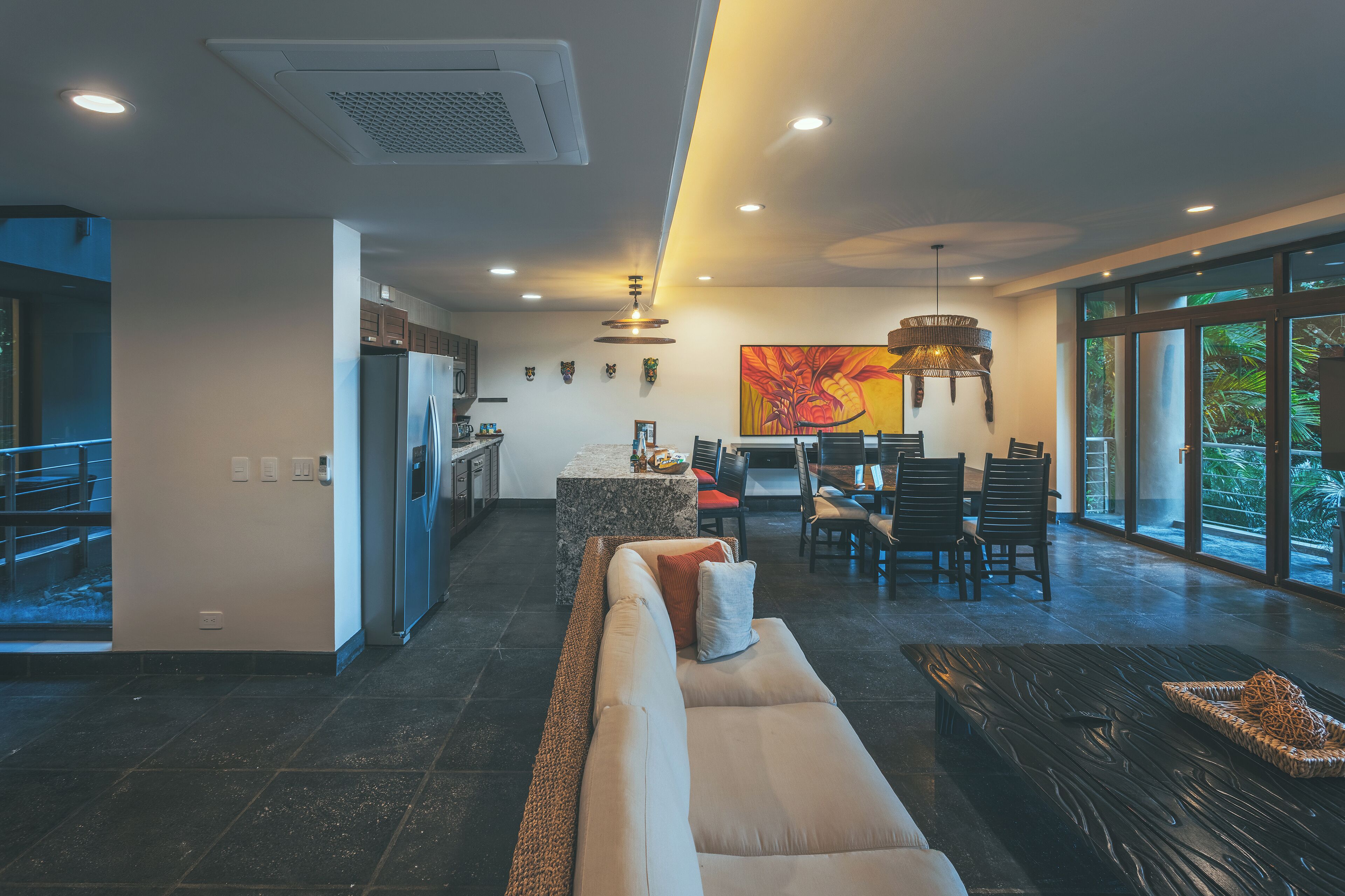 A modern living space with a kitchen, dining area, and large windows.