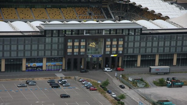 Un edificio moderno con un restaurante Subway, un estacionamiento y un estadio al fondo.