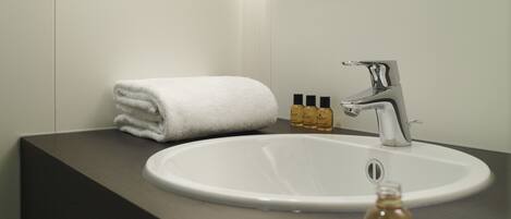 A modern bathroom with a white sink, a mirror, and a towel.