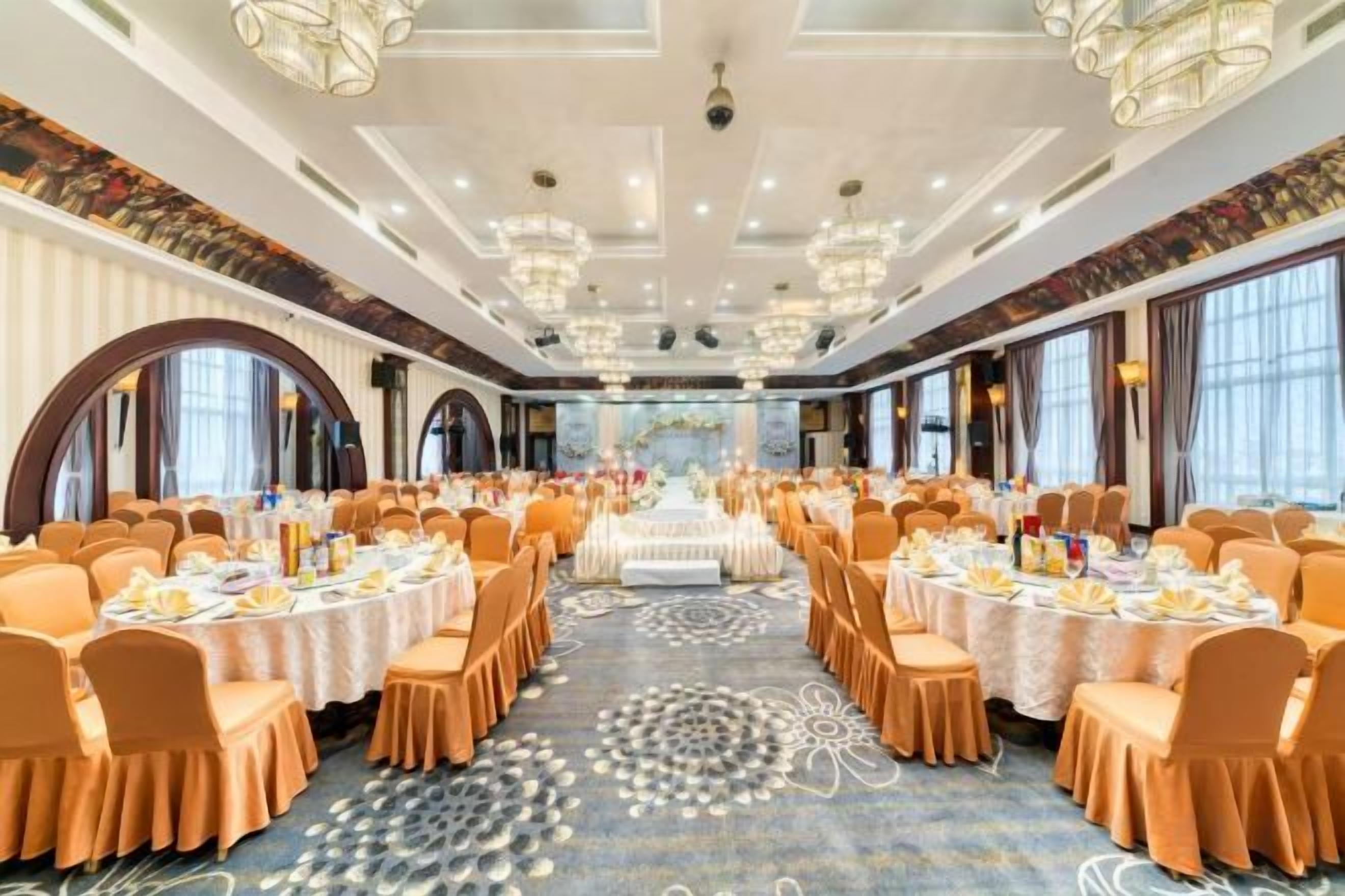 A banquet hall with round tables, chairs, and a central stage.