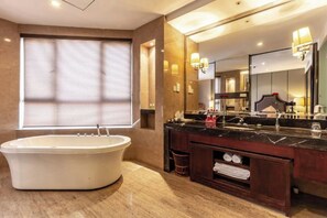 A modern bathroom with a freestanding bathtub, a large mirror, and a vanity with a dark countertop. - Hangzhou International Airport Mingri Hotel (Hangzhou)
