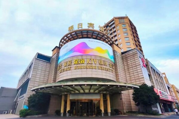 A hotel with a large circular entrance, a prominent billboard, and a tall adjacent building. - Hangzhou International Airport Mingri Hotel (Hangzhou)