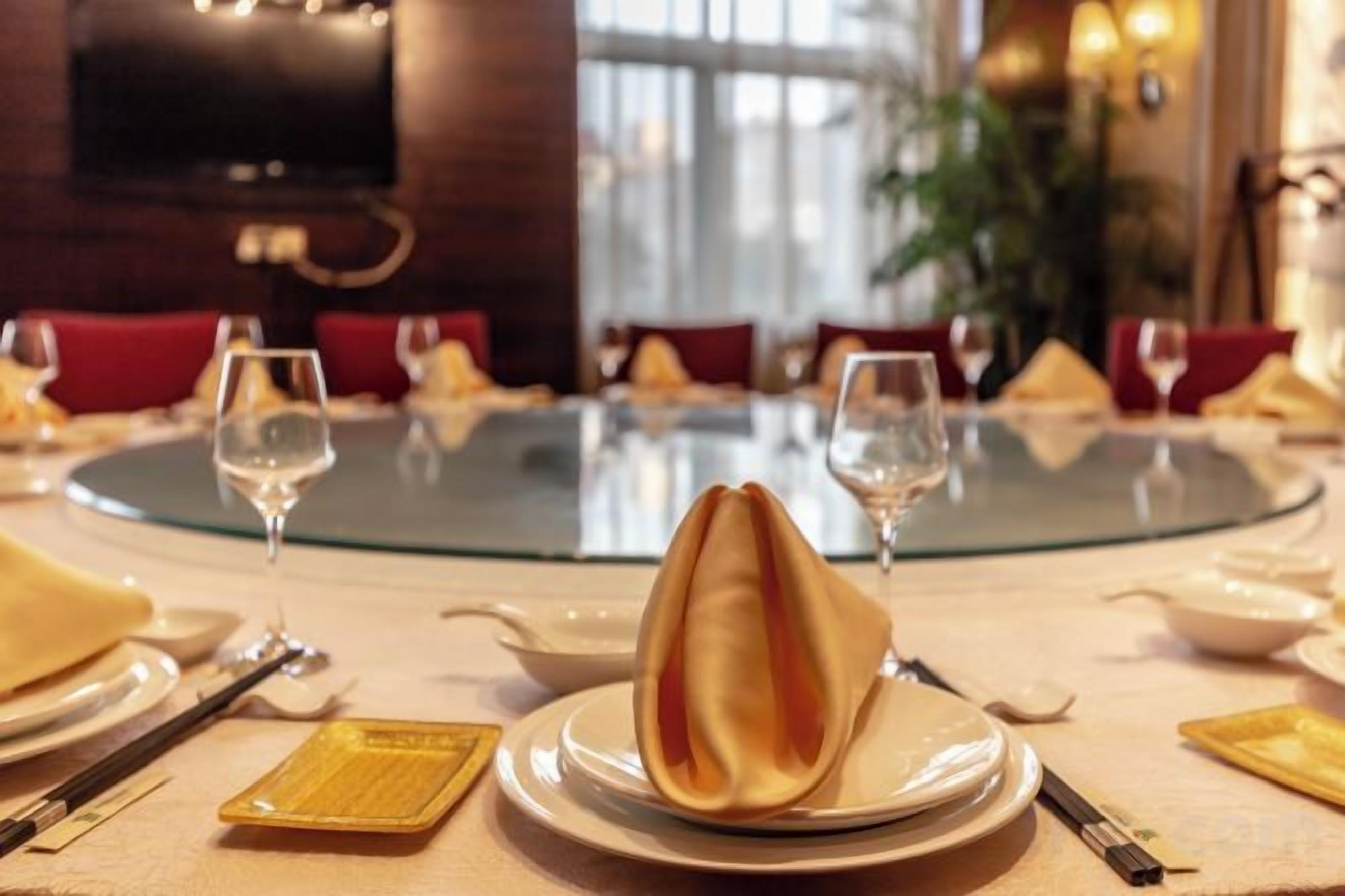 Una mesa de comedor redonda con un plato en el centro, rodeada de sillas y copas de vino.