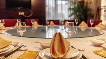 Una mesa de comedor redonda con un plato en el centro, rodeada de sillas y copas de vino.