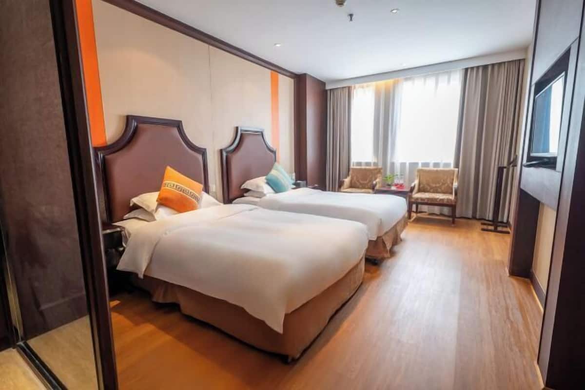 Habitación de hotel con dos camas, un sofá, un televisor y un balcón con cortinas.