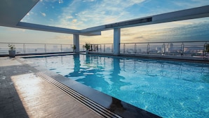 A rooftop infinity pool with clear blue water, surrounded by a modern architectural design with large pillars and a metal railing. - Romance Hotel (Hue)
