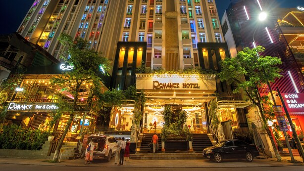 A multi-story hotel with a prominent entrance, a bar and coffee shop on the ground floor, and a well-lit facade. - Romance Hotel (Hue)