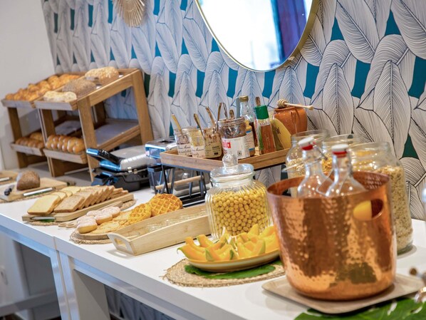A buffet table with various food items, including bread, pastries, and condiments.