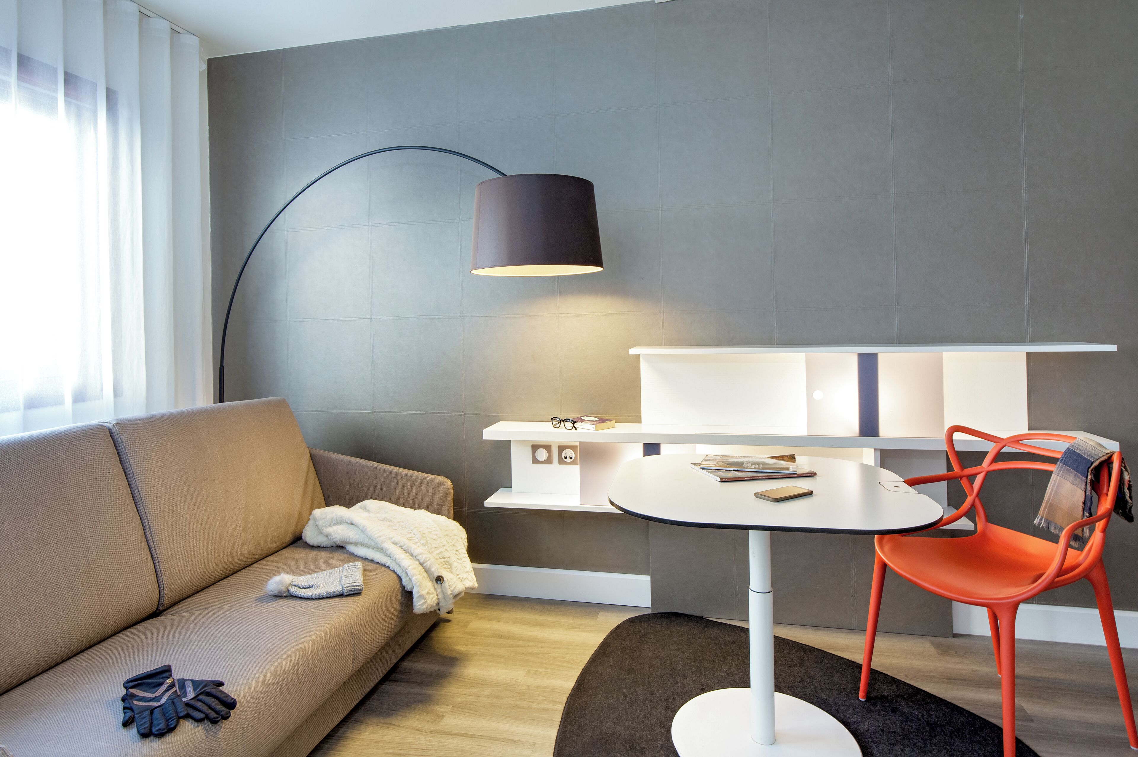 A modern living room with a sofa, a round table, and a red chair.