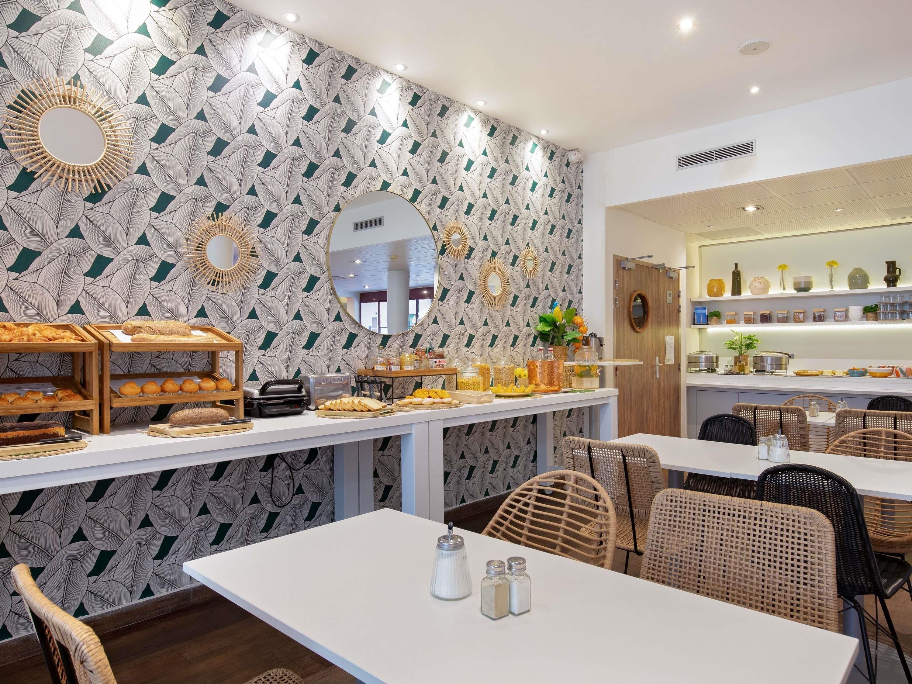 Un bufé de desayuno con diversas opciones de comida y una pared decorativa con motivos de hojas.