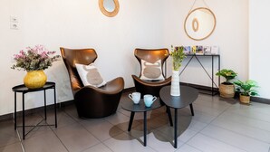 A modern waiting area with two leather chairs, a small table with a vase of flowers, and a wall-mounted display with informational brochures.